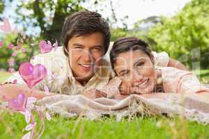 Composite image of two friends lying together on a blanket while