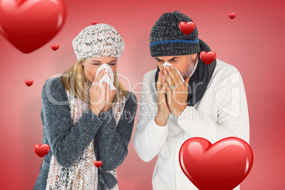 Composite image of sick couple in winter fashion sneezing