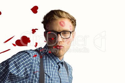 Composite image of geeky hipster covered in kisses