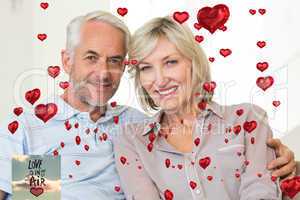 Composite image of smiling mature couple sitting on sofa with ar