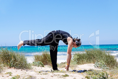 man doing pilates exercises on beach in summer