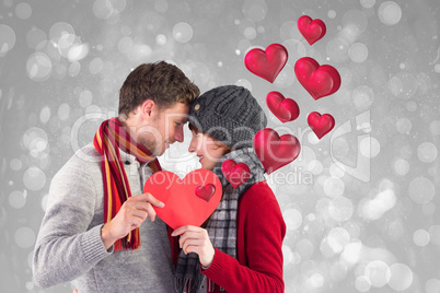 Composite image of couple holding a red heart