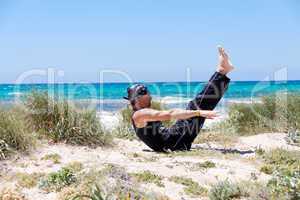 man doing pilates exercises on beach in summer