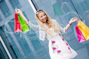 smiling blonde woman with colorful bags on shopping tour