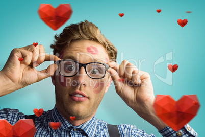 Composite image of geeky hipster covered in kisses