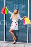 smiling blonde woman with colorful bags on shopping tour