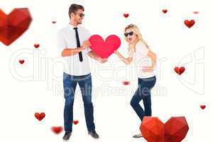 Composite image of cool young couple holding red heart