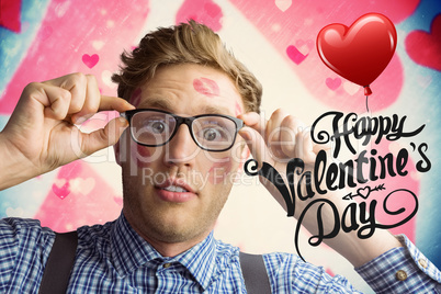 Composite image of geeky hipster covered in kisses