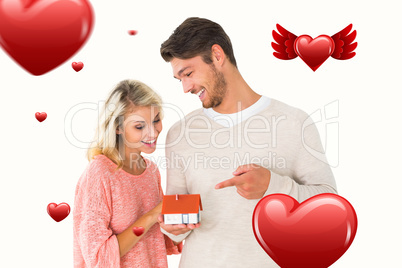 Composite image of attractive couple holding miniature house mod