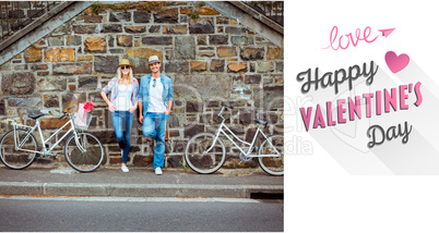 Composite image of hip young couple standing by brick wall with