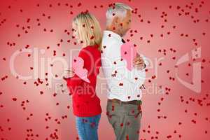 Composite image of couple holding two halves of broken heart