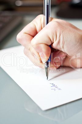 womans hand is writing a letter with a pen