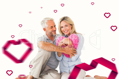 Composite image of happy couple sitting and holding heart pillow