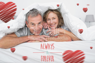 Composite image of cheerful couple under the duvet