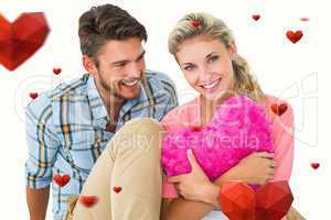 Composite image of attractive young couple sitting holding heart