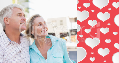 Composite image of happy mature couple sitting on bench in the c