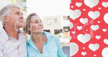 Composite image of happy mature couple sitting on bench in the c