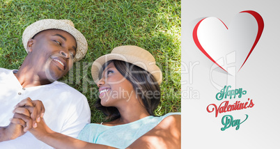 Composite image of happy couple lying in garden together on the