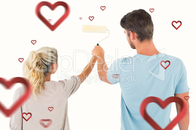 Composite image of young couple painting with roller