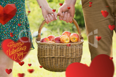 Composite image of basket of apples being carried by a young cou