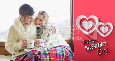 Composite image of loving couple in winter wear with cups agains