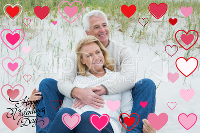 Composite image of romantic senior couple relaxing at beach