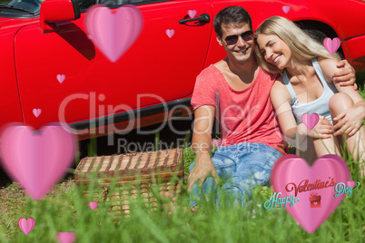 Composite image of smiling couple sitting on the grass having pi