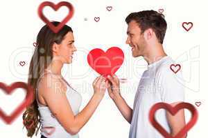 Composite image of romantic young couple holding heart