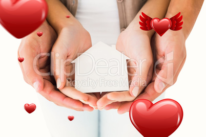 Composite image of couple holding miniature house in hands