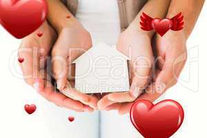 Composite image of couple holding miniature house in hands