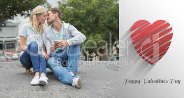 Composite image of hip young couple sitting on skateboard kissin