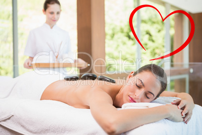 Composite image of beautiful woman receiving stone massage at he