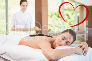 Composite image of beautiful woman receiving stone massage at he