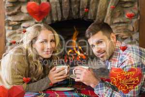 Composite image of couple with tea cups in front of lit fireplac