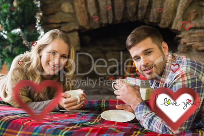 Composite image of smiling couple with tea cups in front of lit