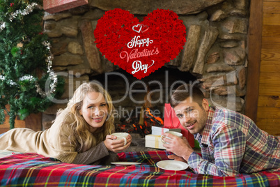 Composite image of couple with tea cups in front of lit fireplac