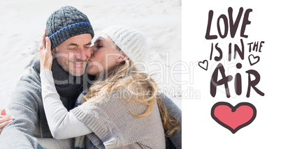 Composite image of attractive couple on the beach in warm clothi