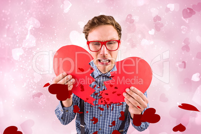 Composite image of geeky hipster holding a broken heart