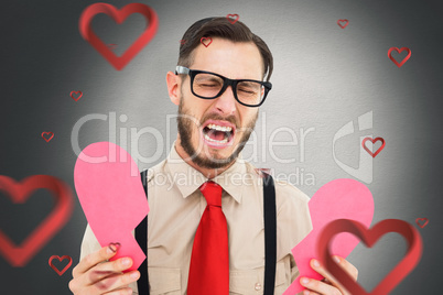 Composite image of geeky hipster crying and holding broken heart
