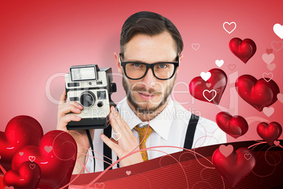 Composite image of geeky hipster holding a retro camera