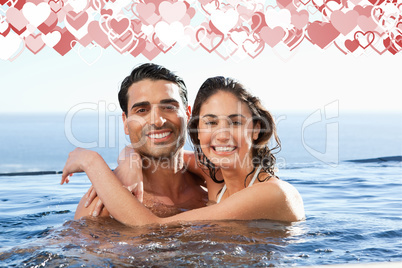 Composite image of smiling couple embracing in the pool