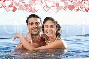 Composite image of smiling couple embracing in the pool