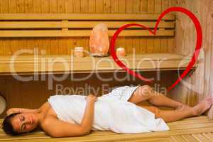 Composite image of happy brunette woman lying in a sauna