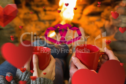 Composite image of hands with red coffee cups in front of lit fi