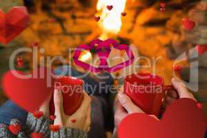 Composite image of hands with red coffee cups in front of lit fi