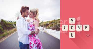 Composite image of cute couple standing on the road hugging