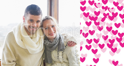 Composite image of couple in winter clothing sitting against win