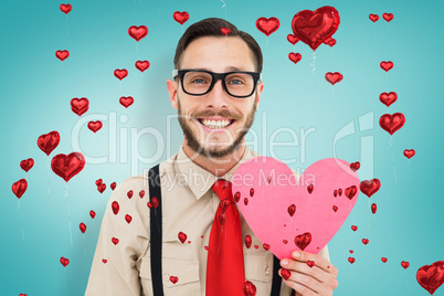 Composite image of geeky hipster smiling and holding heart card