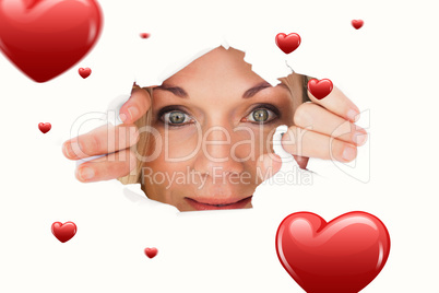 Composite image of woman looking through torn paper