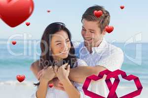 Composite image of cheerful couple relaxing on the beach during